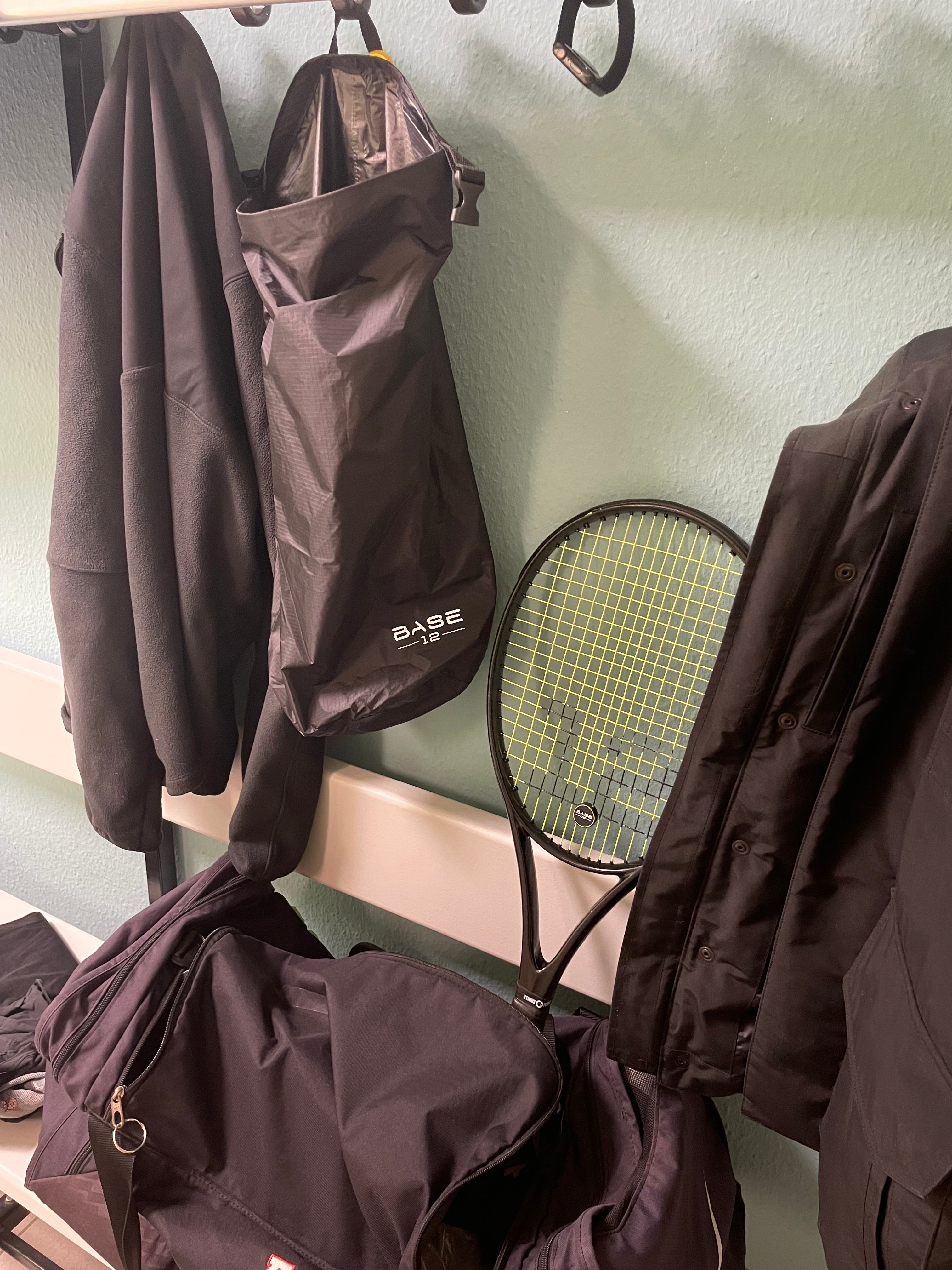 Tennisschläger und BASE12 Sweat Bag hängen in einer Umkleide nach dem Training