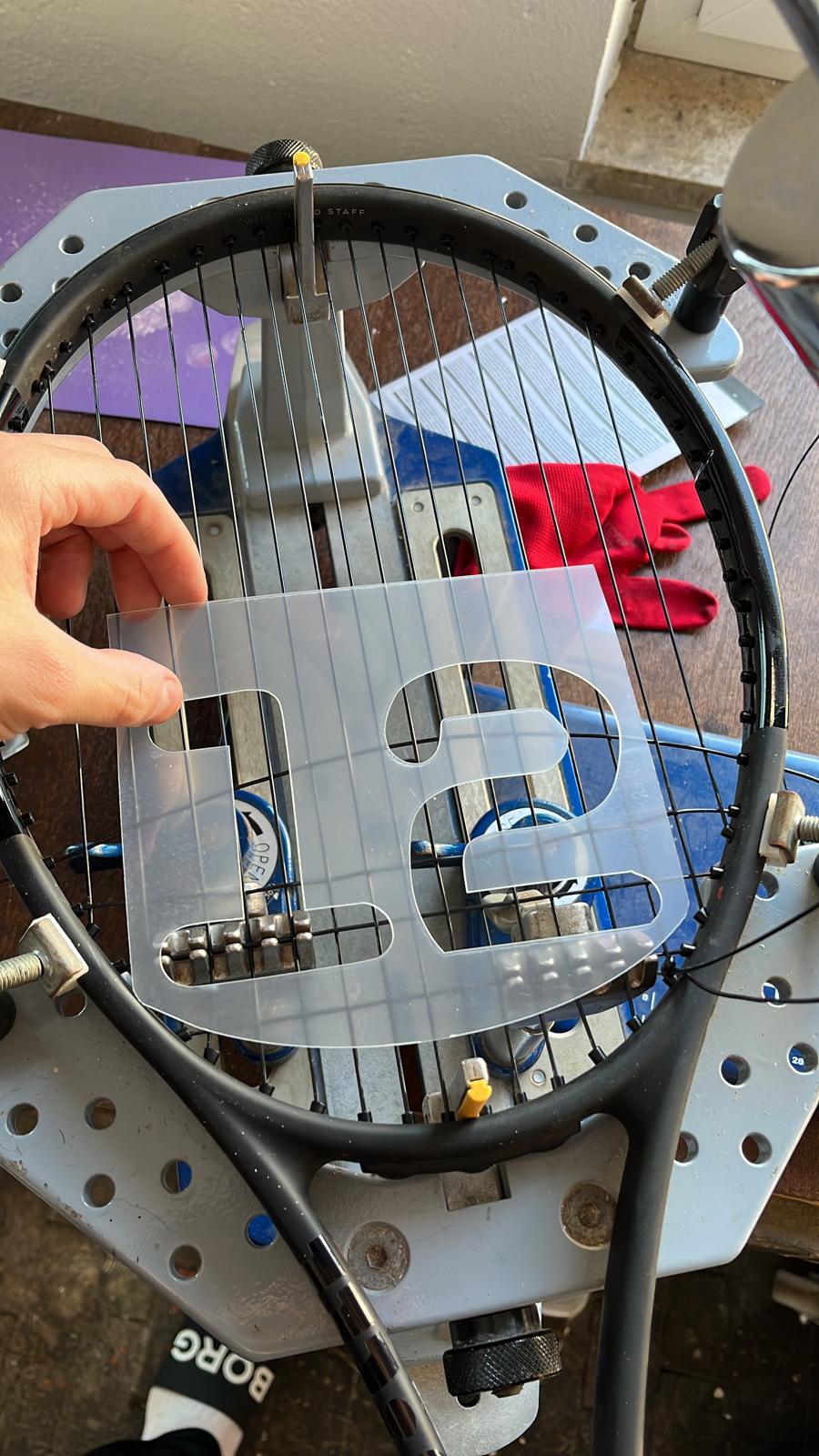 Tennisschläger wird mit einer BASE12 Tennissaite auf einer Bespannmaschine bespannt