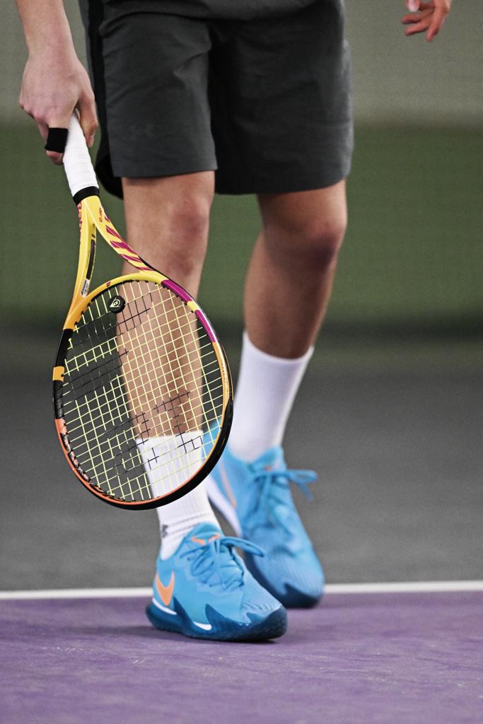 Tennisspieler hält einen Tennisschläger während eines Ballwechsels auf dem Platz